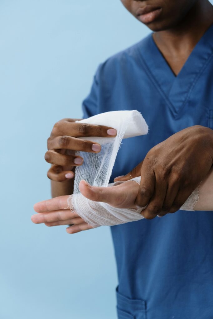 pexels-photo-5721552-5721552 A healthcare professional wrapping a patient's hand with gauze for injury care.